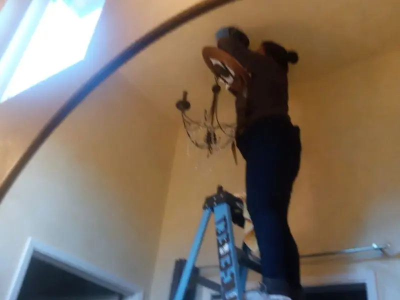 Electrician installing a chandelier in a Merrifield residence